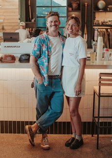 Anna and James Ashton standing in front of the counter at their cheese shop, surrounded by shelves of artisanal cheeses at Ashtons Fromagerie in Broadway Market, Hackney